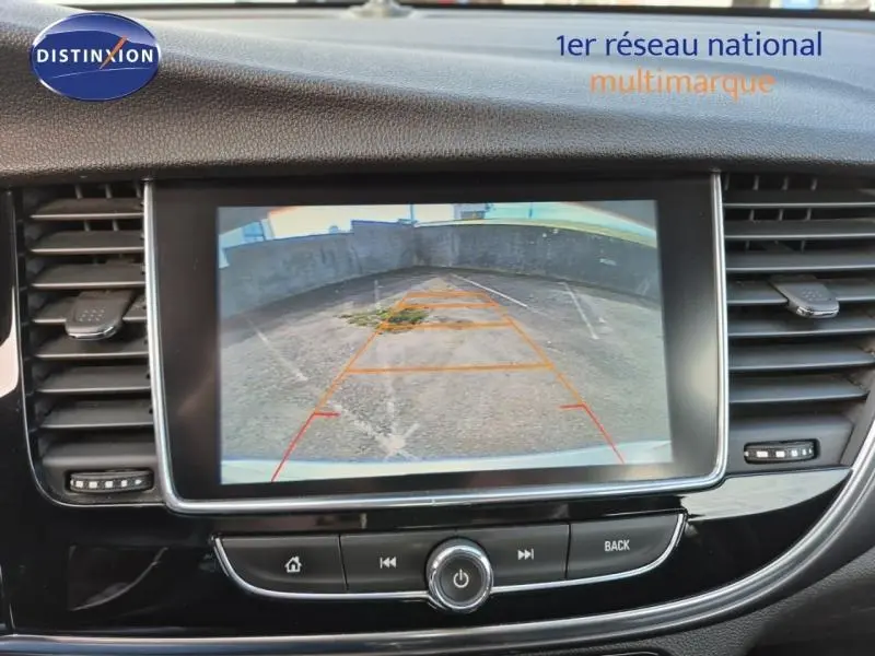 Écran central de l’Opel Mokka X 2018 affichant la caméra de recul avec vue sur un parking bétonné.