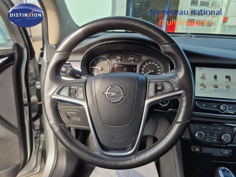 Vue intérieure centrée sur le volant cuir multifonction de l'Opel Mokka X, avec tableau de bord et écran tactile visibles.