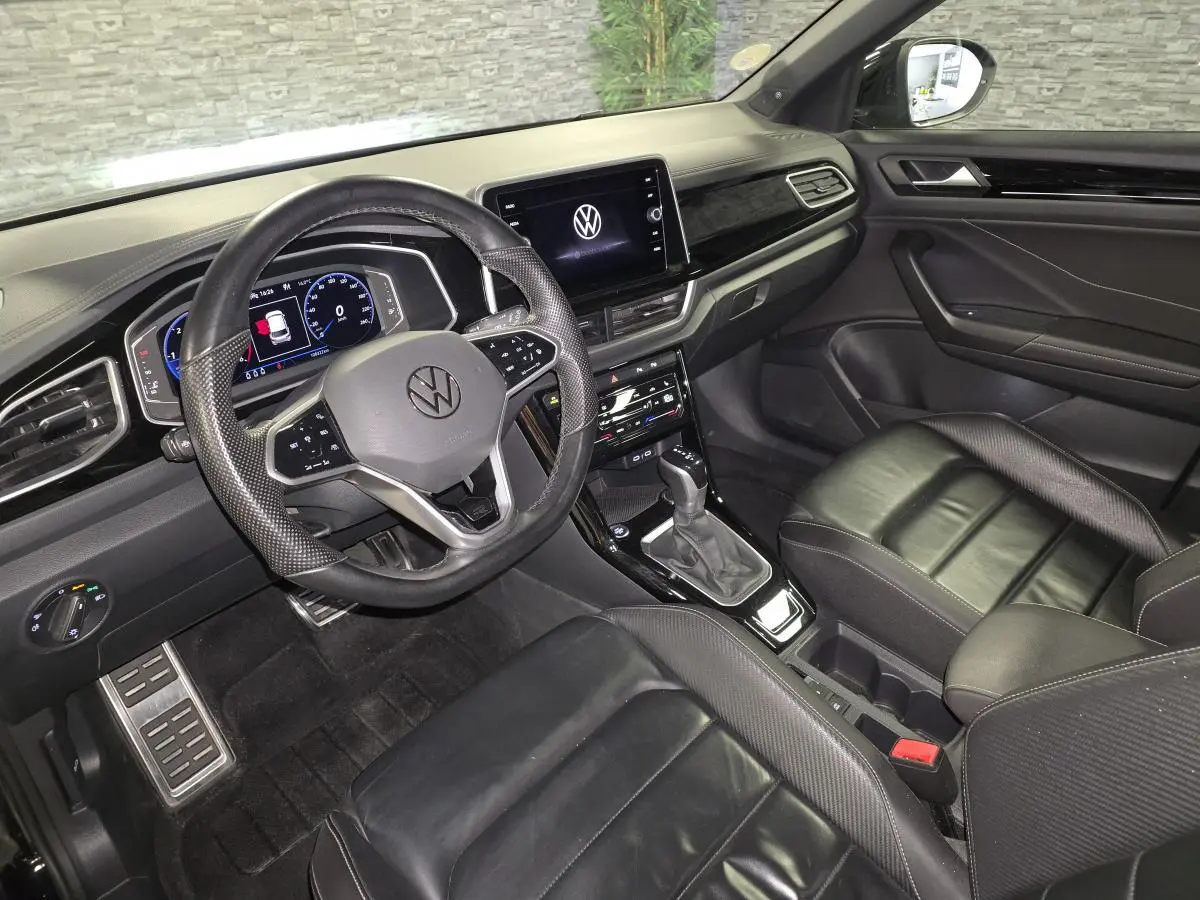 Vue intérieure côté conducteur du Volkswagen T-Roc 2023 noir, avec sellerie cuir Nappa et tableau de bord Piano Noir.