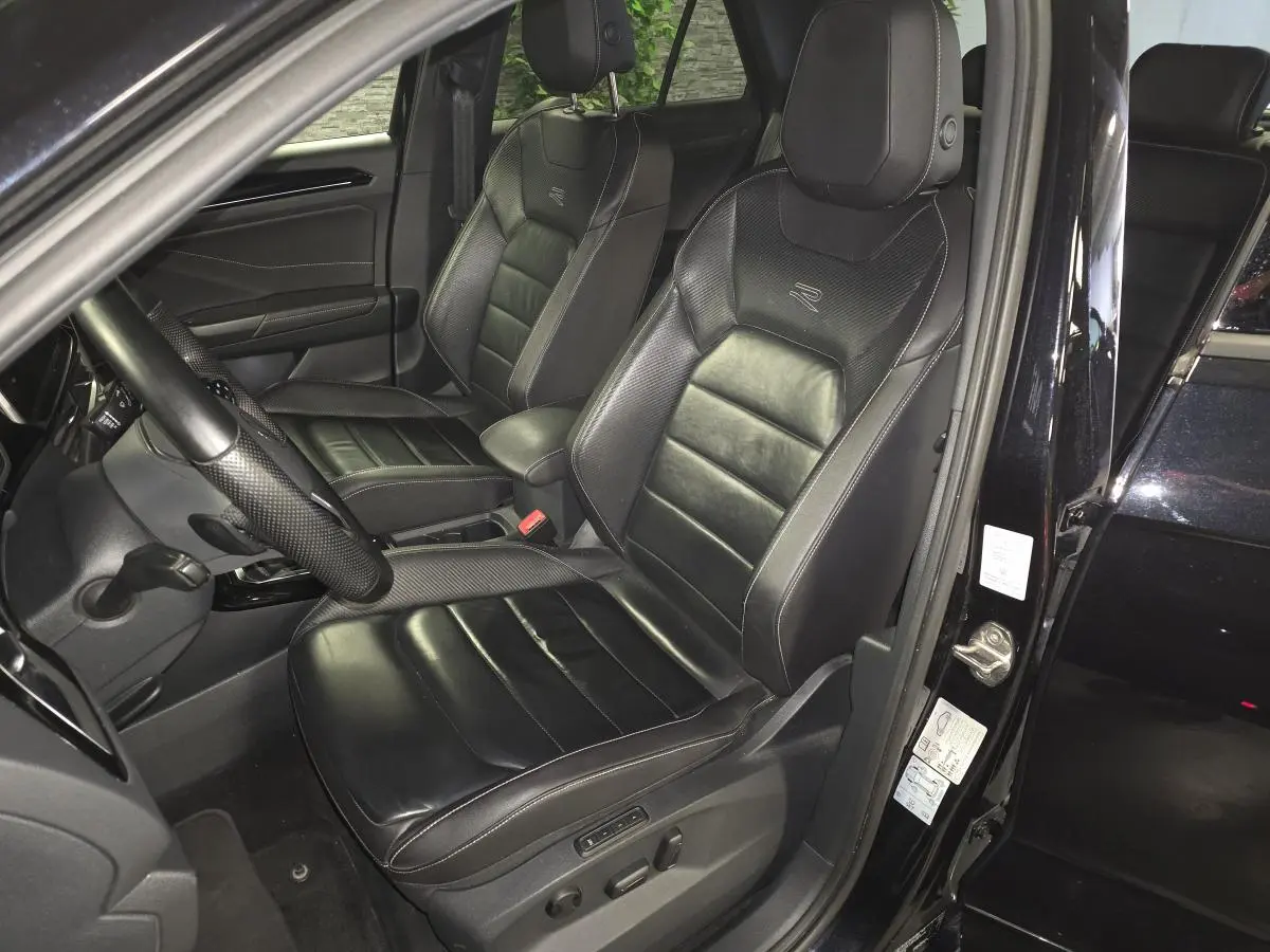 Vue intérieure côté conducteur du Volkswagen T-Roc noir 2023, sièges cuir Nappa R-Line avec réglages électriques et logo R-Line.