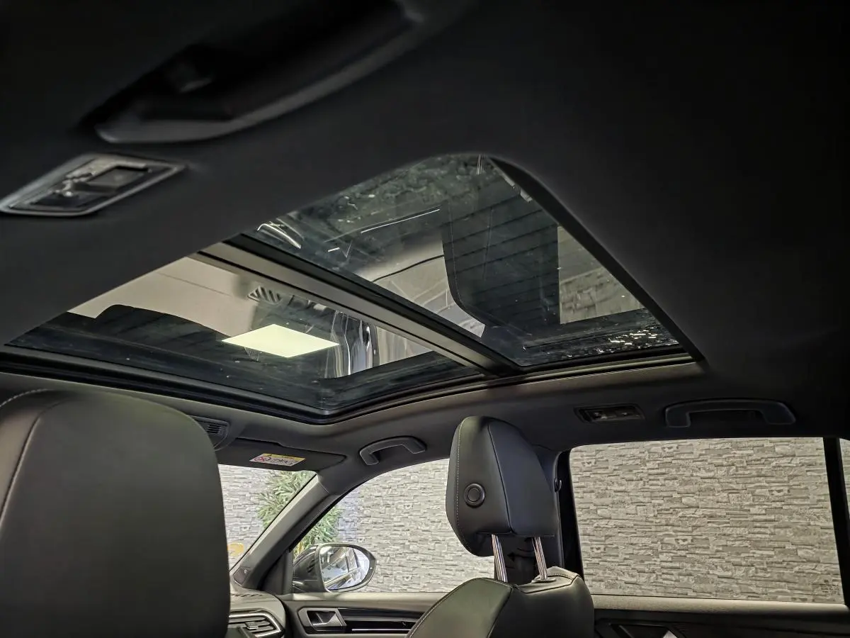 Vue intérieure du toit ouvrant panoramique en verre du Volkswagen T-Roc noir avec sièges avant en cuir noir.