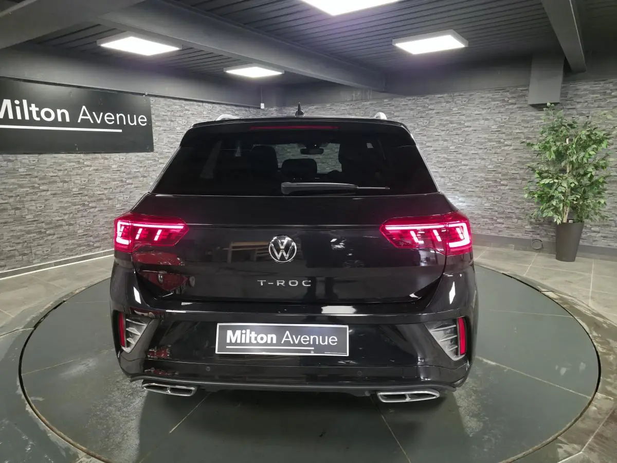Vue arrière d'un Volkswagen T-Roc noir 2023 avec feux LED allumés et double sortie d'échappement rectangulaire.