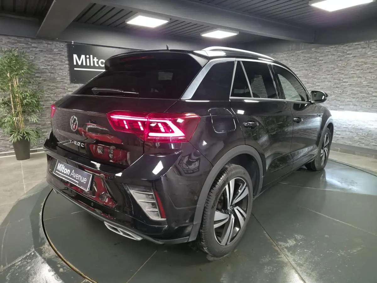 Volkswagen T-Roc noir en 3/4 arrière droit, avec feux arrière LED allumés et jantes alliage Nevada 18 pouces.