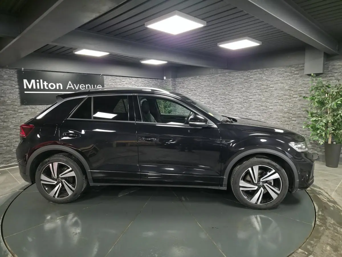 Volkswagen T-Roc noir vue de profil côté gauche, avec jantes alliage distinctives et toit ouvrant en verre.
