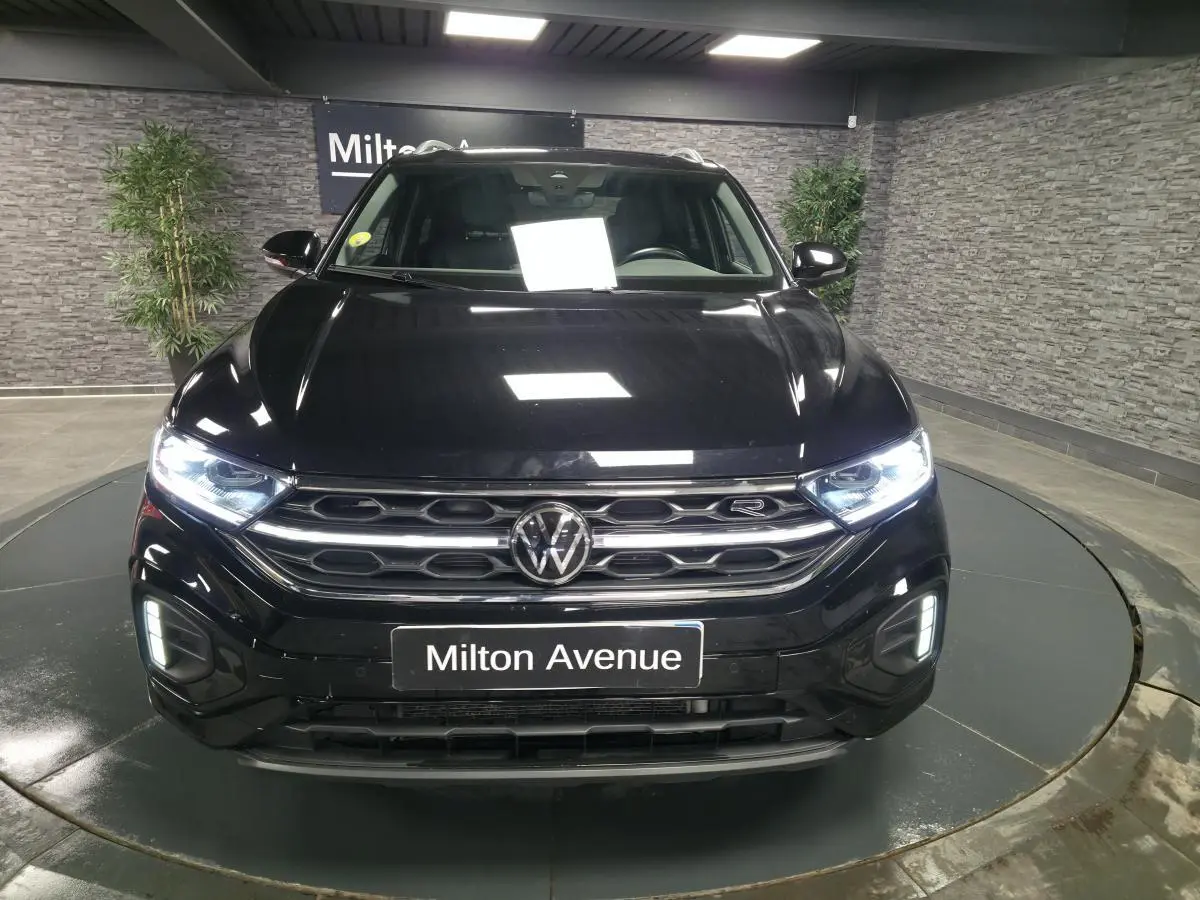 Vue frontale d'un Volkswagen T-Roc noir 2023 avec calandre R-Line et phares Matrix LED allumés.