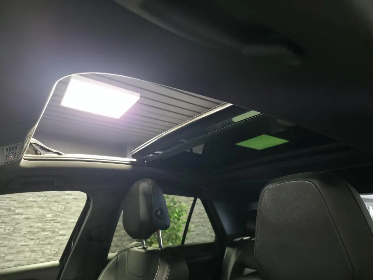 Vue intérieure du toit ouvrant en verre du Volkswagen T-Roc noir 2023 avec sièges avant en cuir noir.