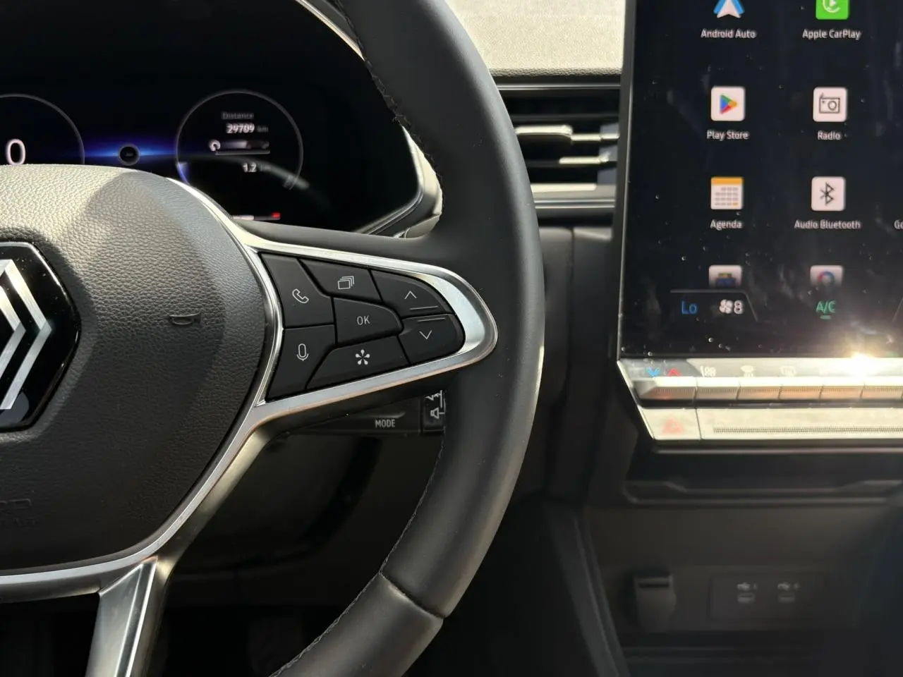 Gros plan sur le volant noir et les commandes multifonctions à droite, avec écran tactile du tableau de bord du Renault Captur TCE 90.