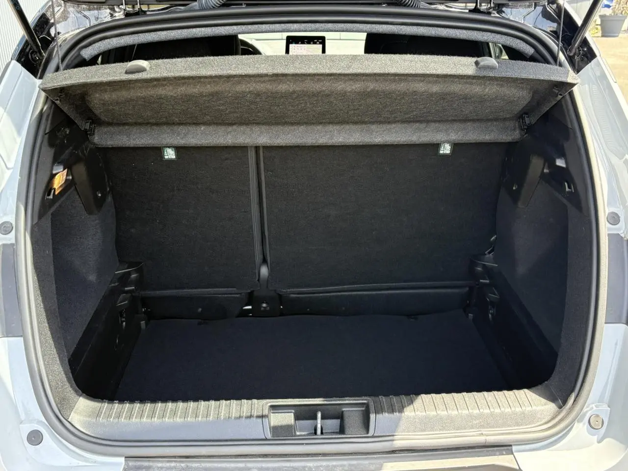 Coffre ouvert vu de l'arrière d'un Renault Captur TCE 90 Techno gris Rafale, montrant l'espace de chargement vide.