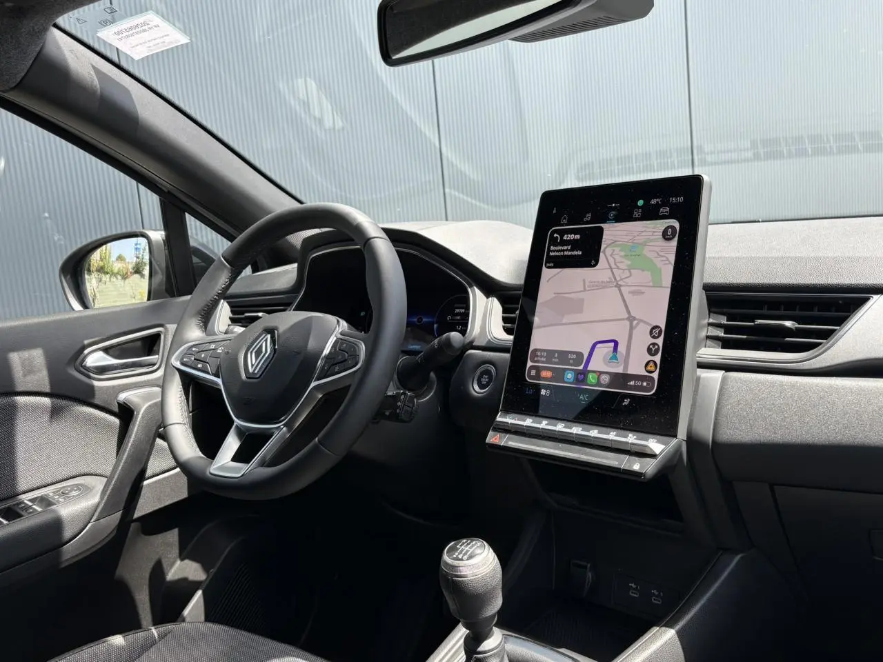 Vue intérieure côté conducteur du Renault Captur TCE 90 Techno 2025, avec tableau de bord numérique et écran GPS vertical.