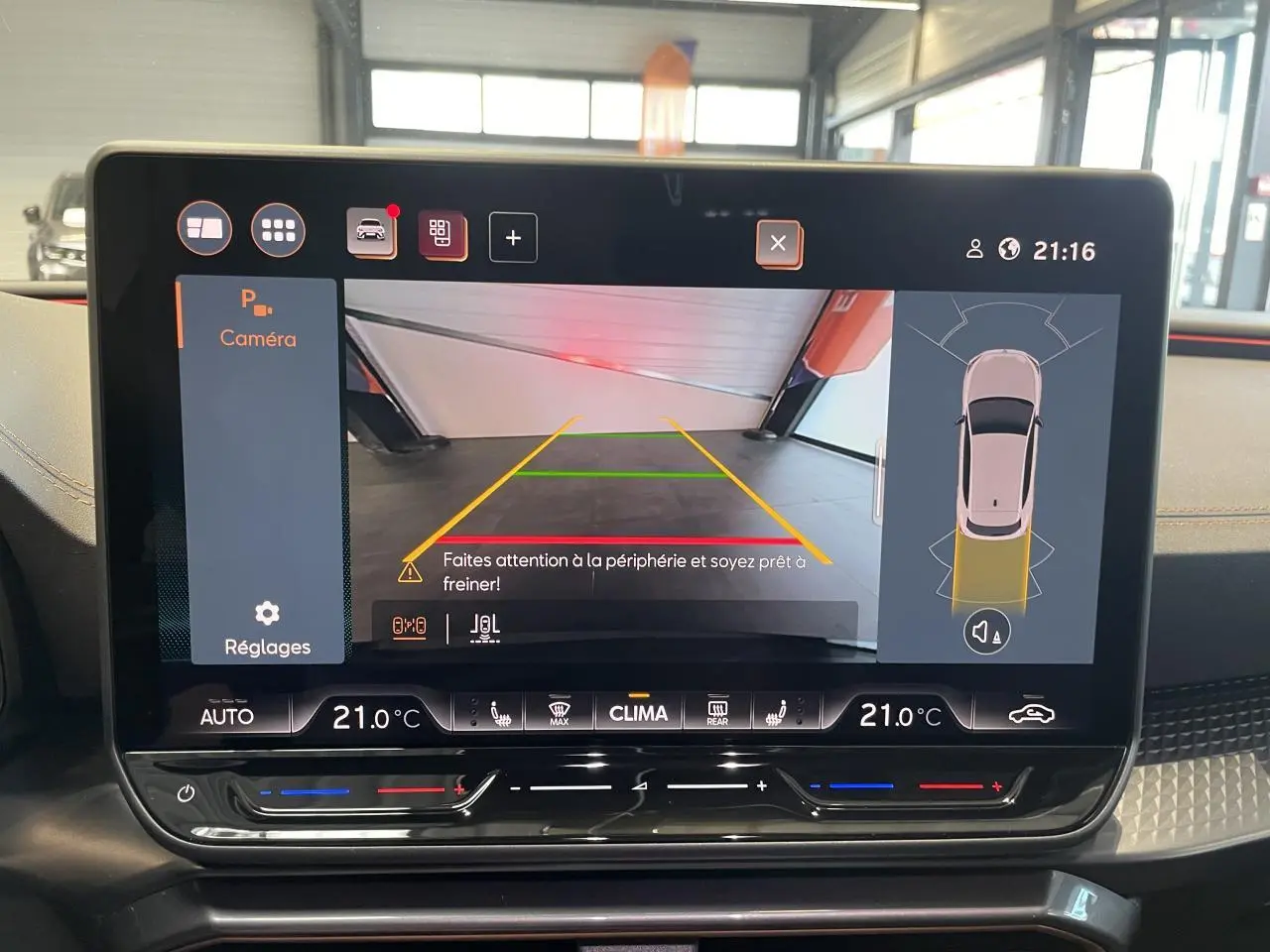 Écran tactile intérieur du CUPRA Leon 2026 montrant la caméra de recul et les réglages de climatisation à 21°C.