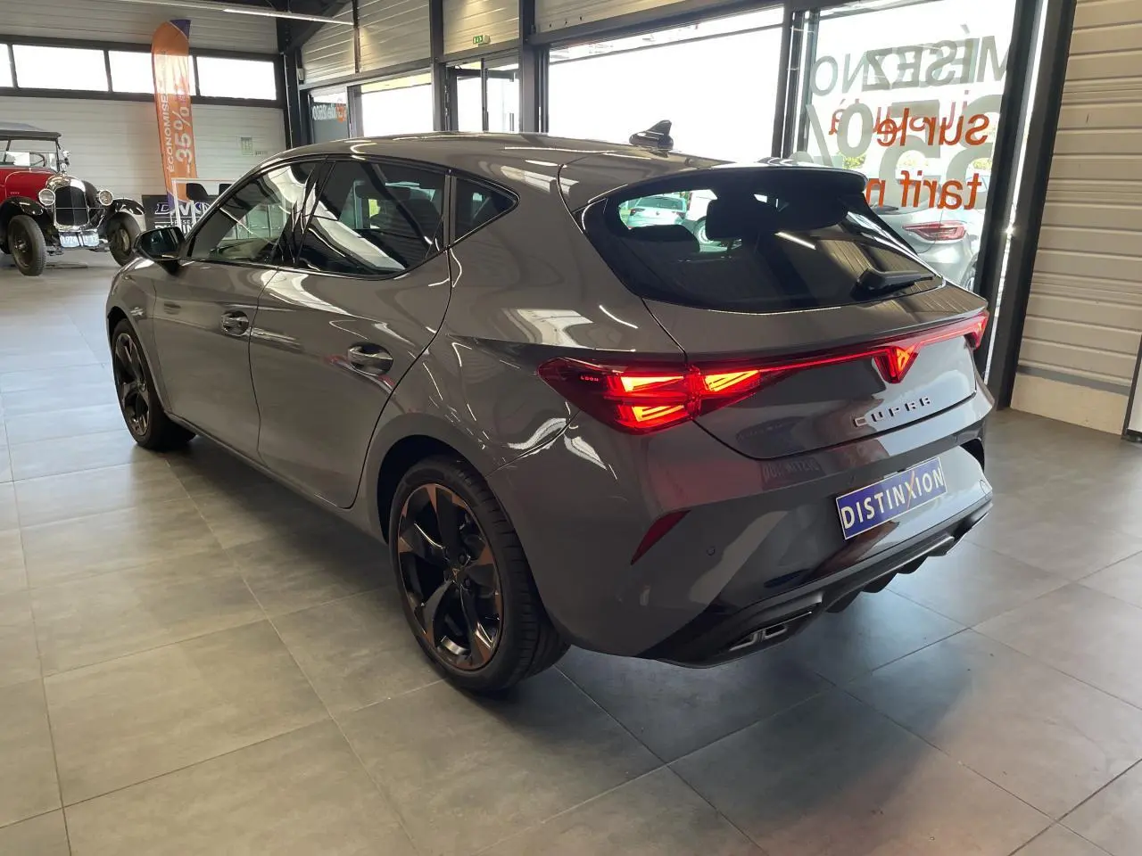 Vue 3/4 arrière droite d'une CUPRA Leon gris magnétique avec feux arrière Tri-LED et jantes alliage 18'' cuivrées.