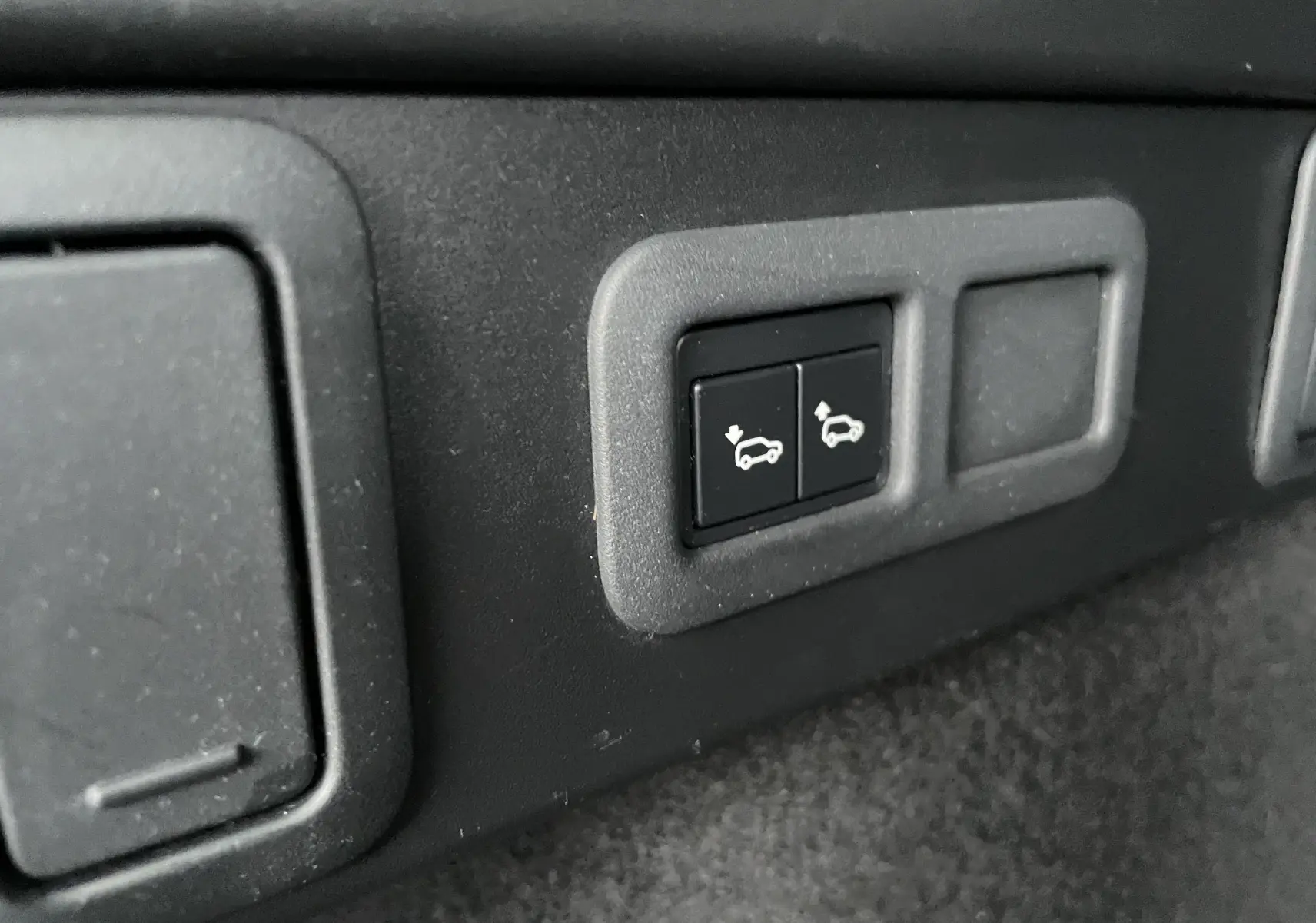 Boutons de commande de l'ouverture et fermeture électrique du hayon dans l'habitacle du Range Rover Velar gris Silicon Silver.