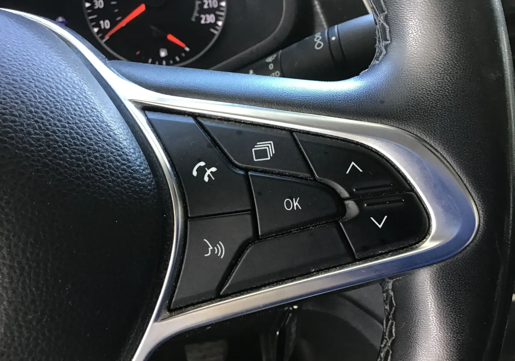 Gros plan sur les commandes noires du volant du Nissan Primastar Fourgon blanc, avec tableau de bord en arrière-plan.