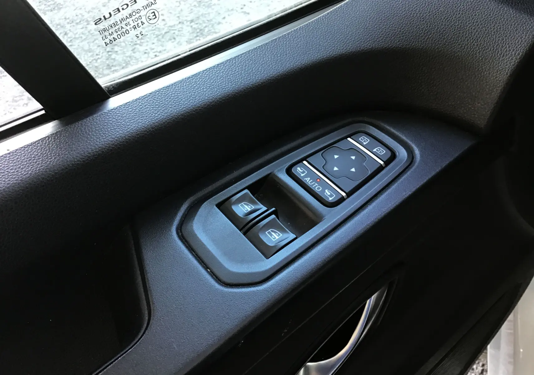 Gros plan sur la commande des vitres et rétroviseurs côté gauche d'un Nissan Primastar blanc, version N-Connecta 2022.