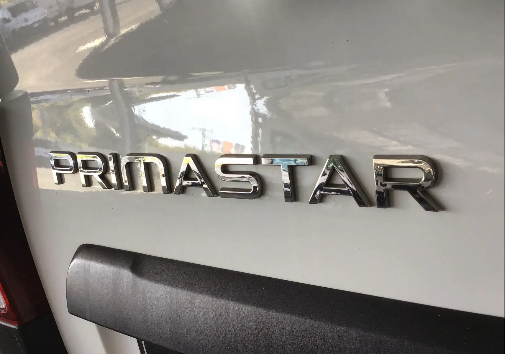 Gros plan sur l'arrière blanc du Nissan Primastar Fourgon avec le logo chromé PRIMASTAR bien visible.