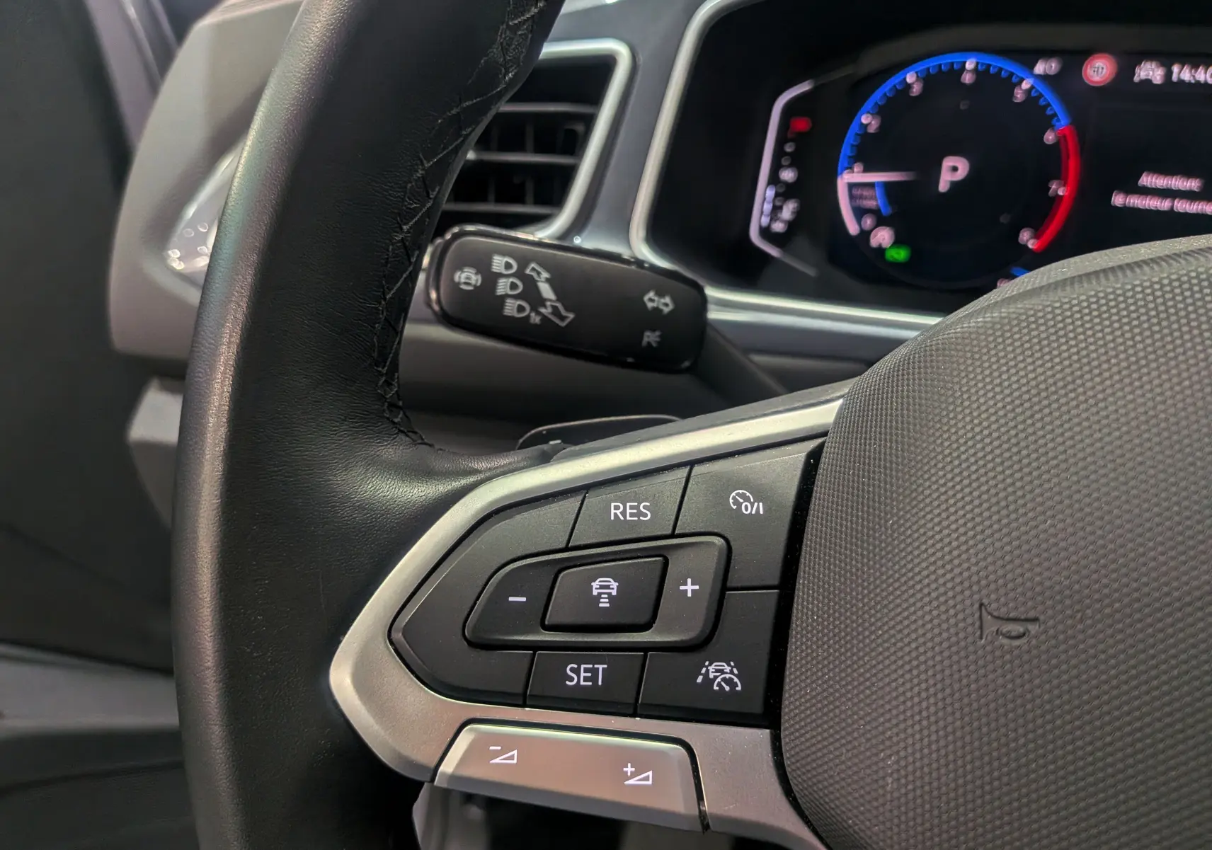 Gros plan sur le volant noir du Volkswagen T-Roc 2024, mettant en valeur les commandes de régulateur de vitesse et l'instrumentation digitale.