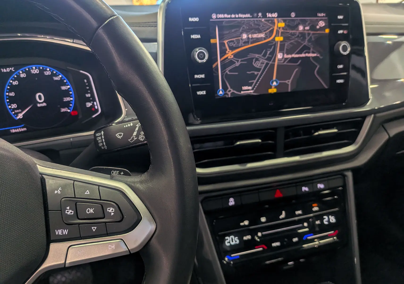 Vue rapprochée de l'intérieur du Volkswagen T-Roc 2024, tableau de bord avec écran tactile et volant en cuir noir.