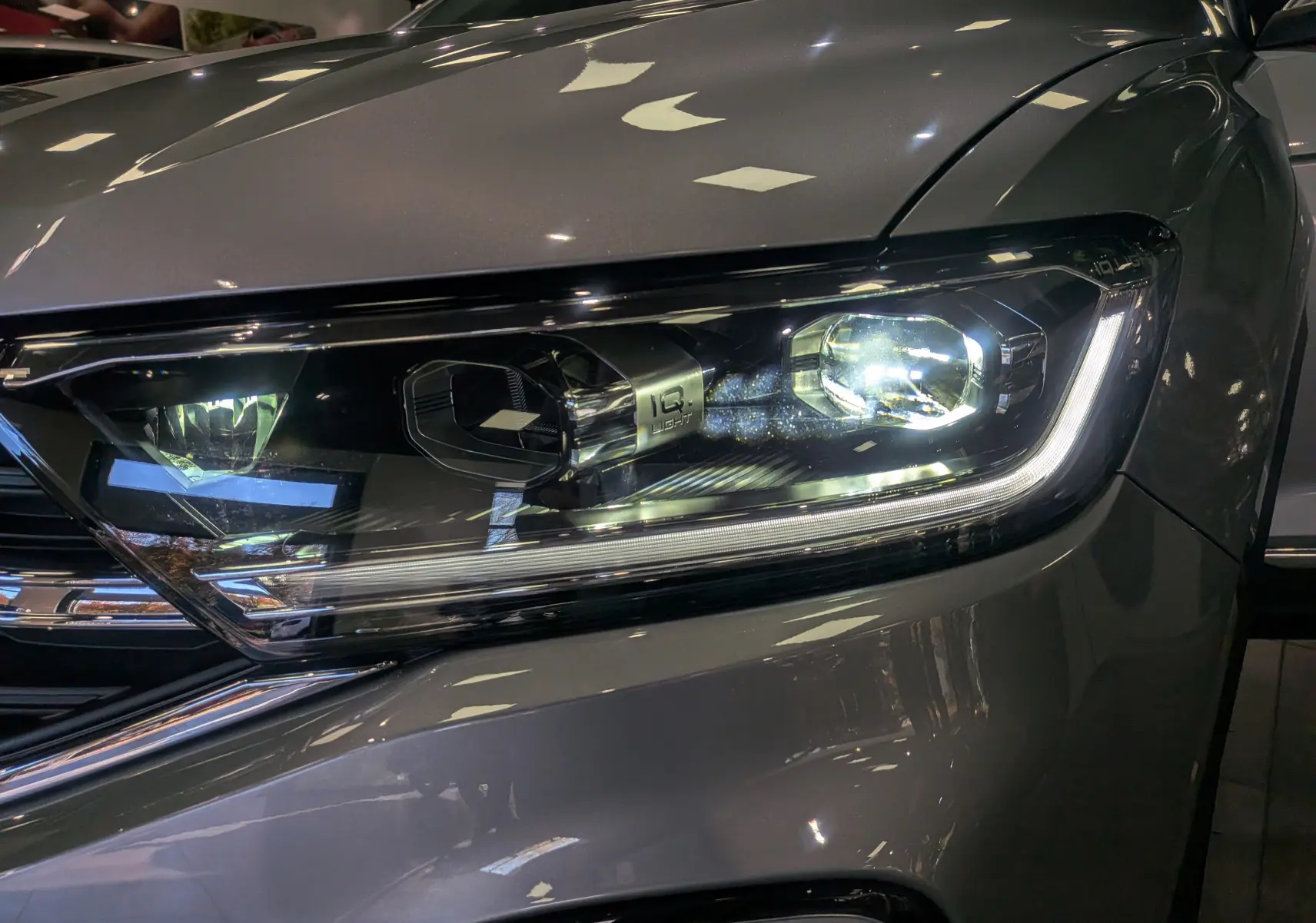 Gros plan sur le phare avant droit du Volkswagen T-Roc 2024 gris pyrite, mettant en valeur la signature lumineuse LED IQ Light.
