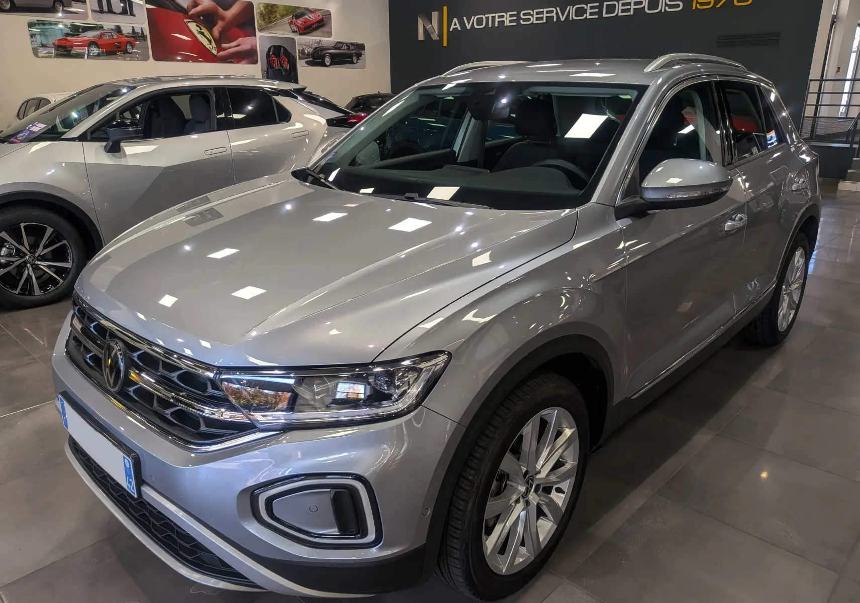 Volkswagen T-Roc 1.5 TSI gris pyrite en 3/4 avant droit, mettant en valeur ses optiques LED et jantes alliage.