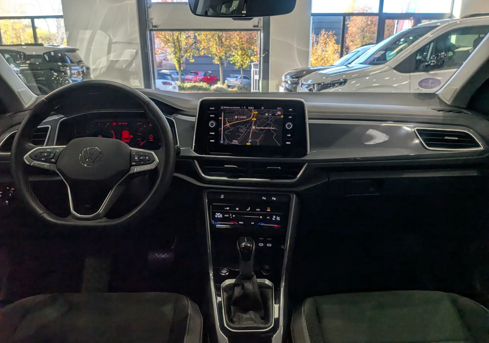 Intérieur du Volkswagen T-Roc 2024 gris pyrite, vue frontale sur le tableau de bord avec écran tactile et volant multifonction.