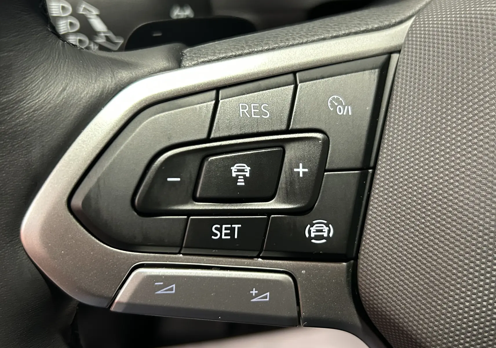 Gros plan sur les commandes de régulateur de vitesse au volant du Volkswagen T-Roc 2025 gris Indium Metal.