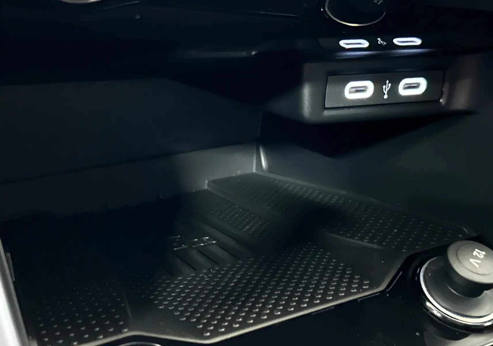 Gros plan sur le compartiment de recharge avec ports USB et prise 12V dans un Volkswagen T-Roc 2025 gris Indium.
