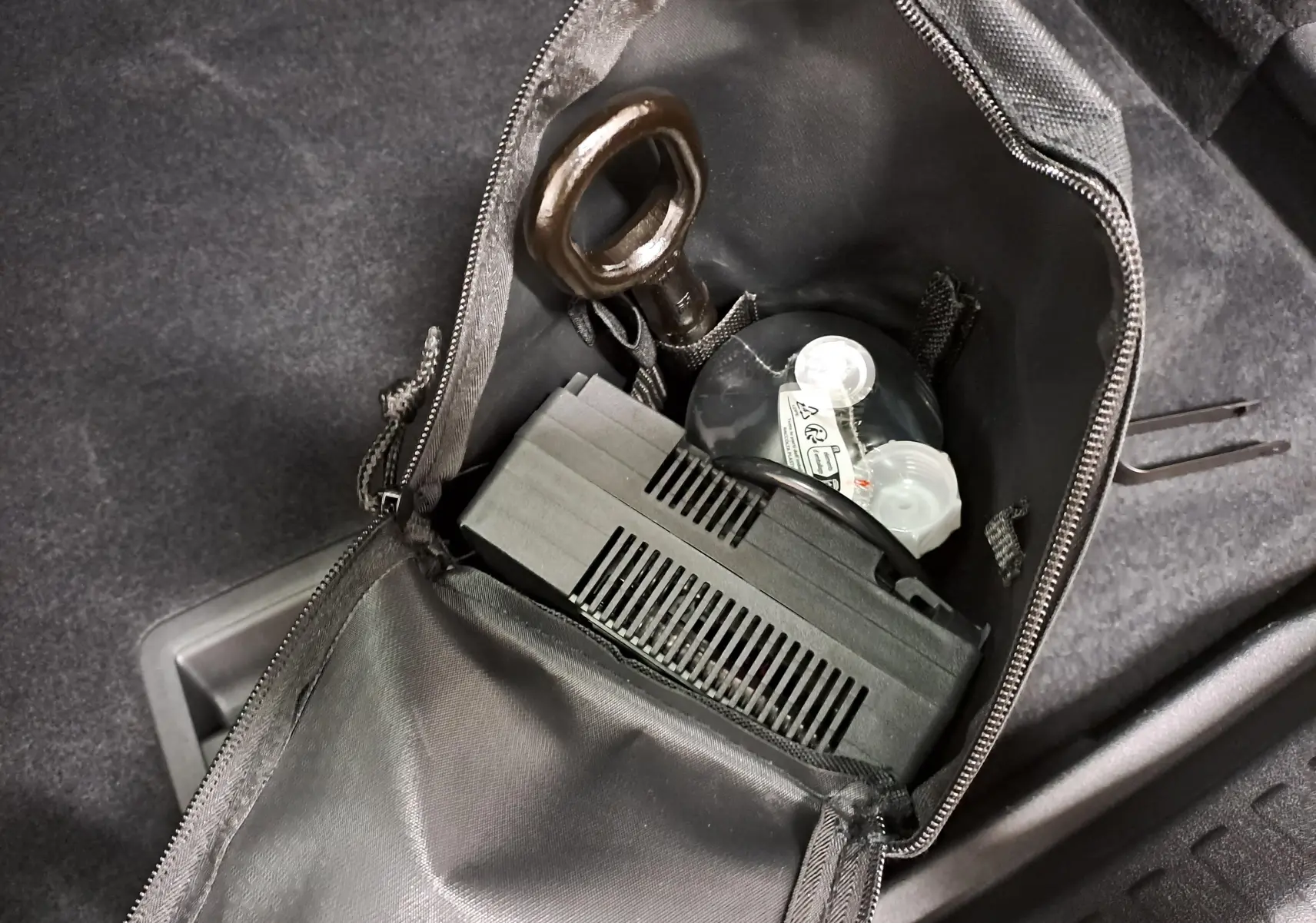 Gros plan sur le kit de secours dans le coffre du CUPRA TERRAMAR 2025, avec pochette noire ouverte et outils visibles.