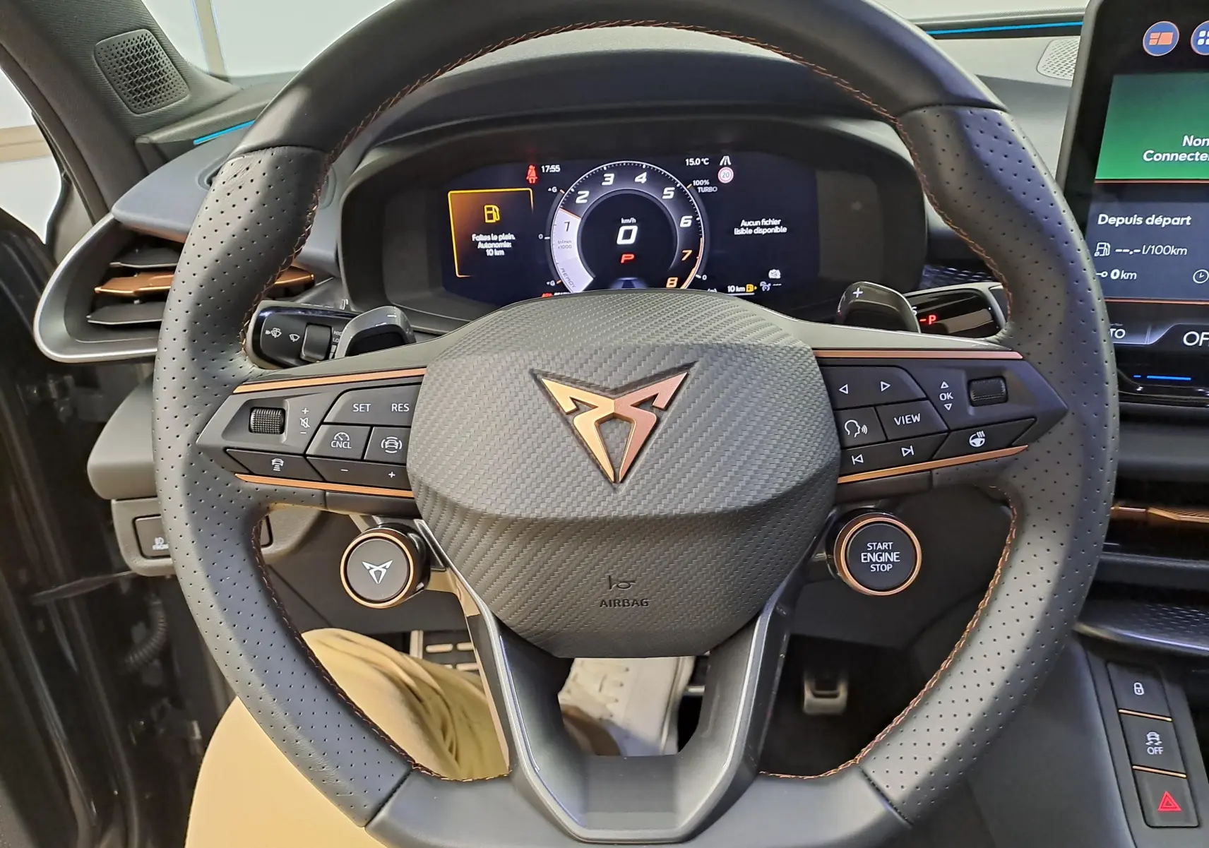 Vue rapprochée du volant perforé avec logo CUPRA cuivré et tableau de bord numérique du CUPRA TERRAMAR gris Timanfaya.