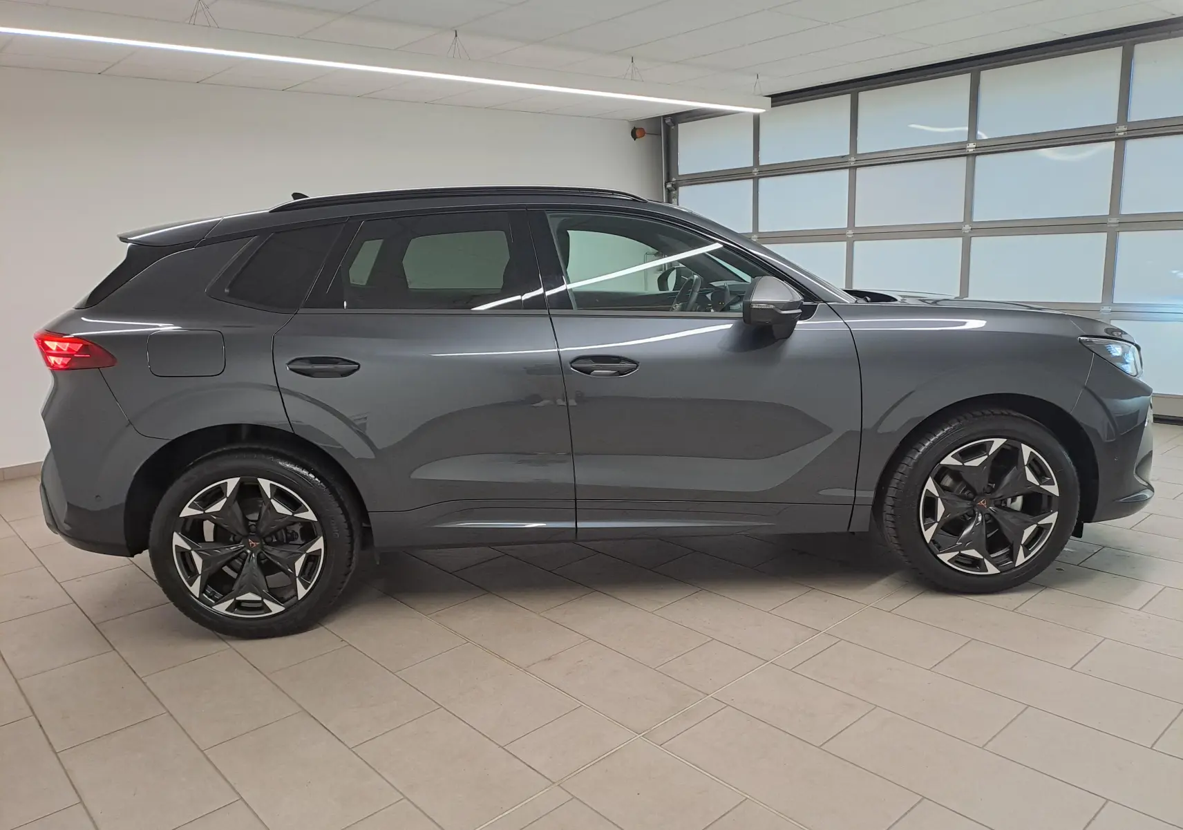 Vue de profil côté gauche d'un CUPRA TERRAMAR gris Timanfaya avec jantes 19'' Cosmic usinées en intérieur lumineux.