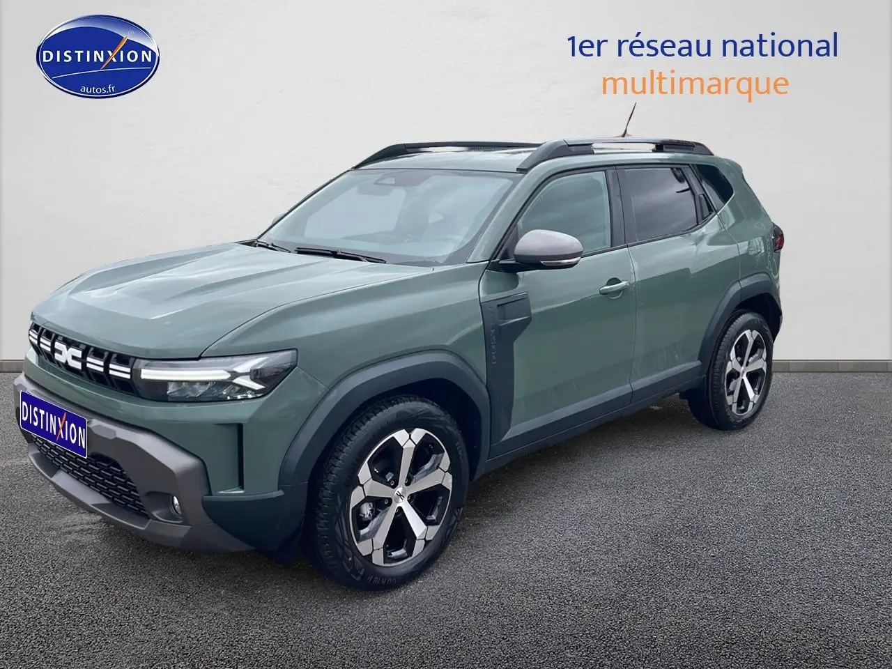 SUV Dacia Duster vert kaki en 3/4 avant droit, avec jantes alu et barres de toit visibles.
