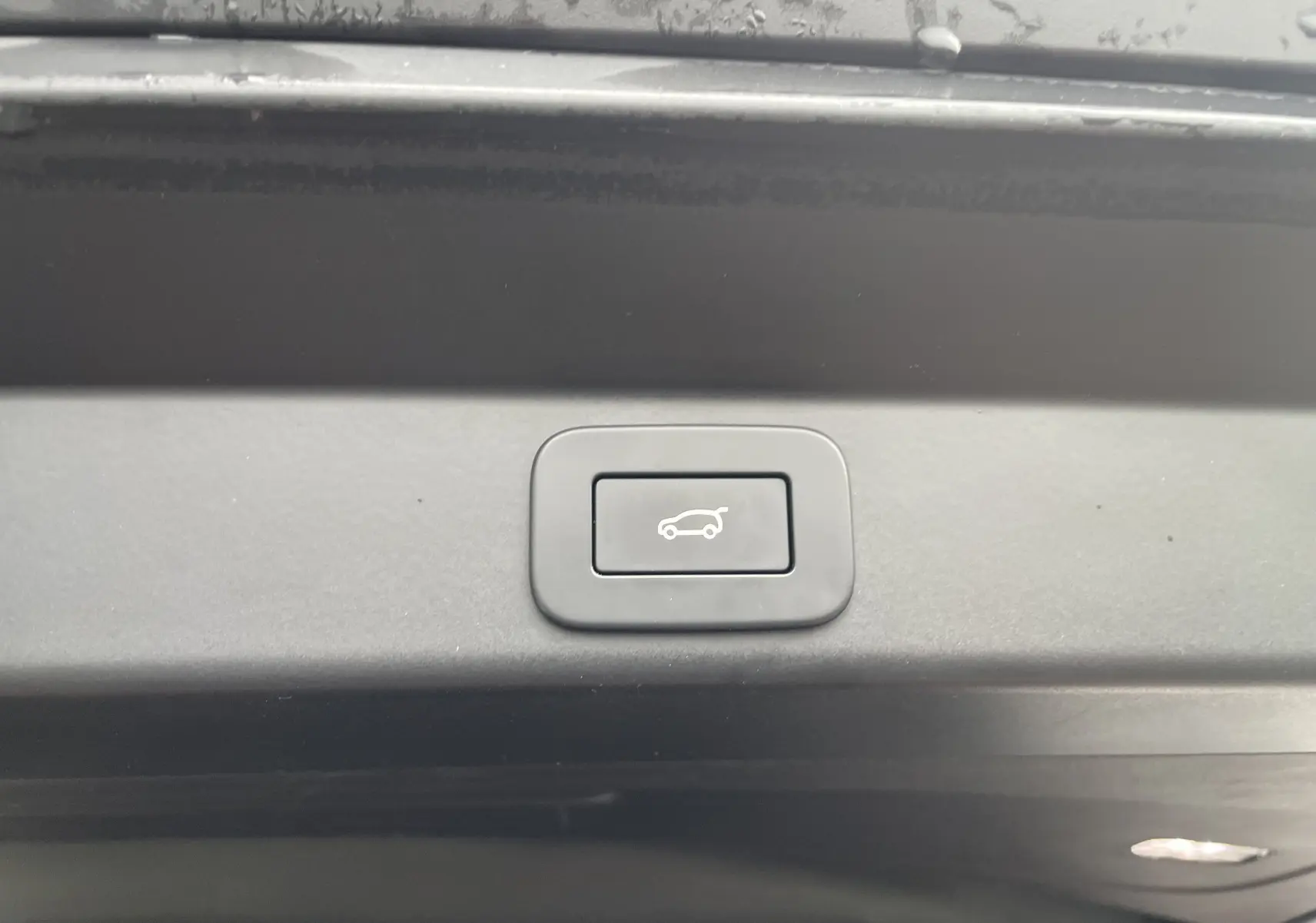 Gros plan sur le bouton d'ouverture électrique du coffre, intérieur noir du Range Rover Sport P440 HSE R-Dynamic 2023.