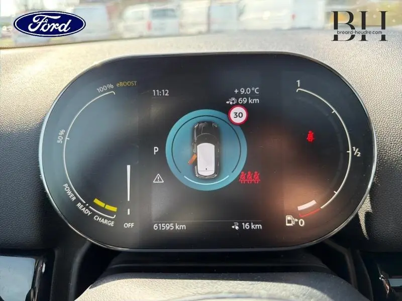 Tableau de bord numérique de MINI Countryman Cooper SE en vue frontale, affichage d'état hybride et informations de conduite.