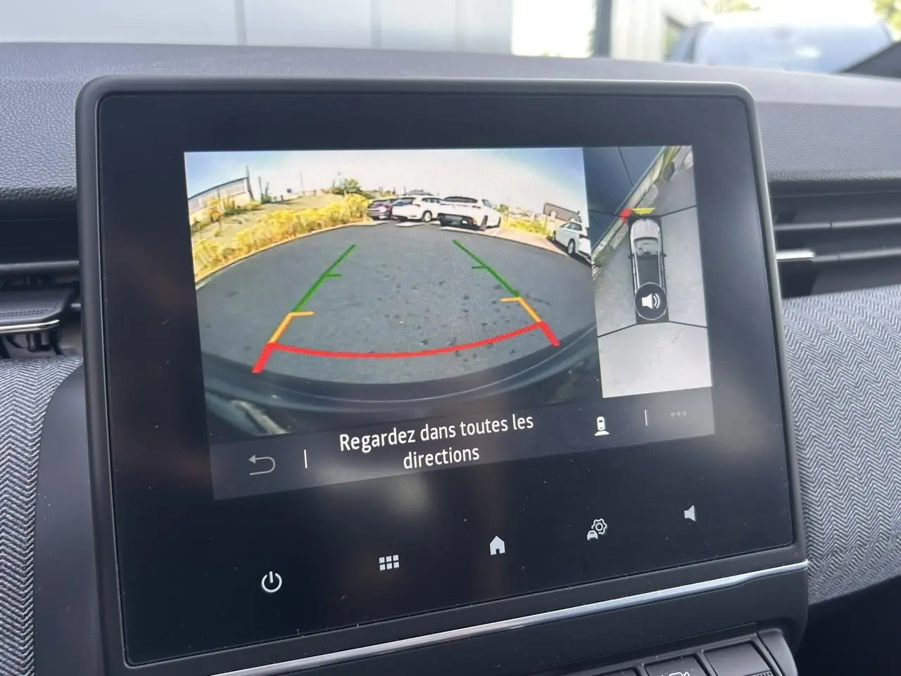 Écran multimédia montrant la caméra 360° en mode recul avec guidage coloré dans un Renault Clio noir étoilé.