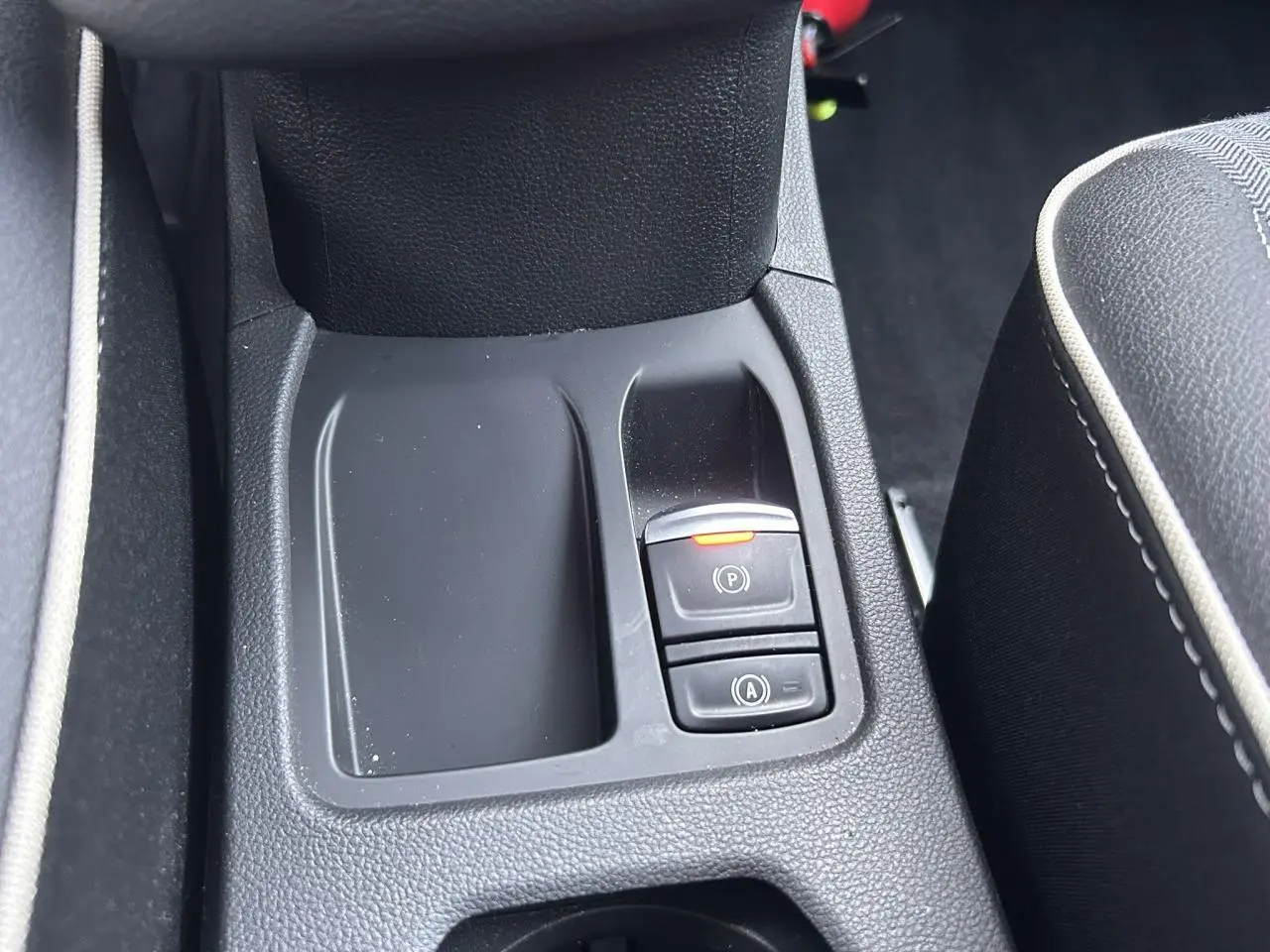 Gros plan sur la console centrale avant de la Renault Clio V TCE 90 Techno noire, avec frein de parking électrique activé.