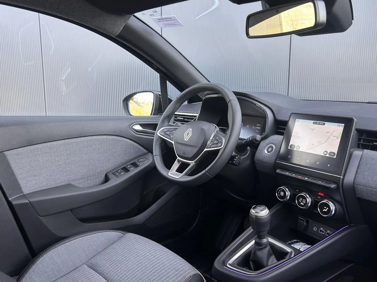 Vue intérieure côté conducteur de la Renault Clio 2025 noir étoilé avec volant multifonction et écran tactile central.