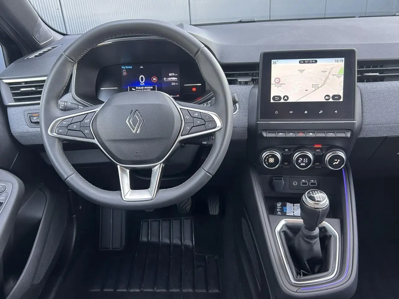 Vue intérieure frontale du tableau de bord de la Renault Clio noir étoilé avec volant multifonction et écran tactile central.