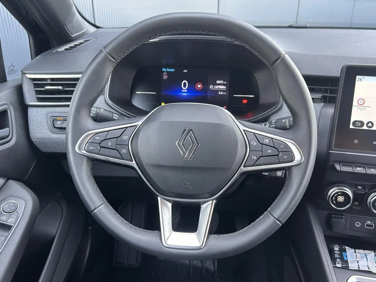 Vue rapprochée du volant multifonction noir de la Renault Clio 2025 avec tableau de bord numérique et écran tactile.