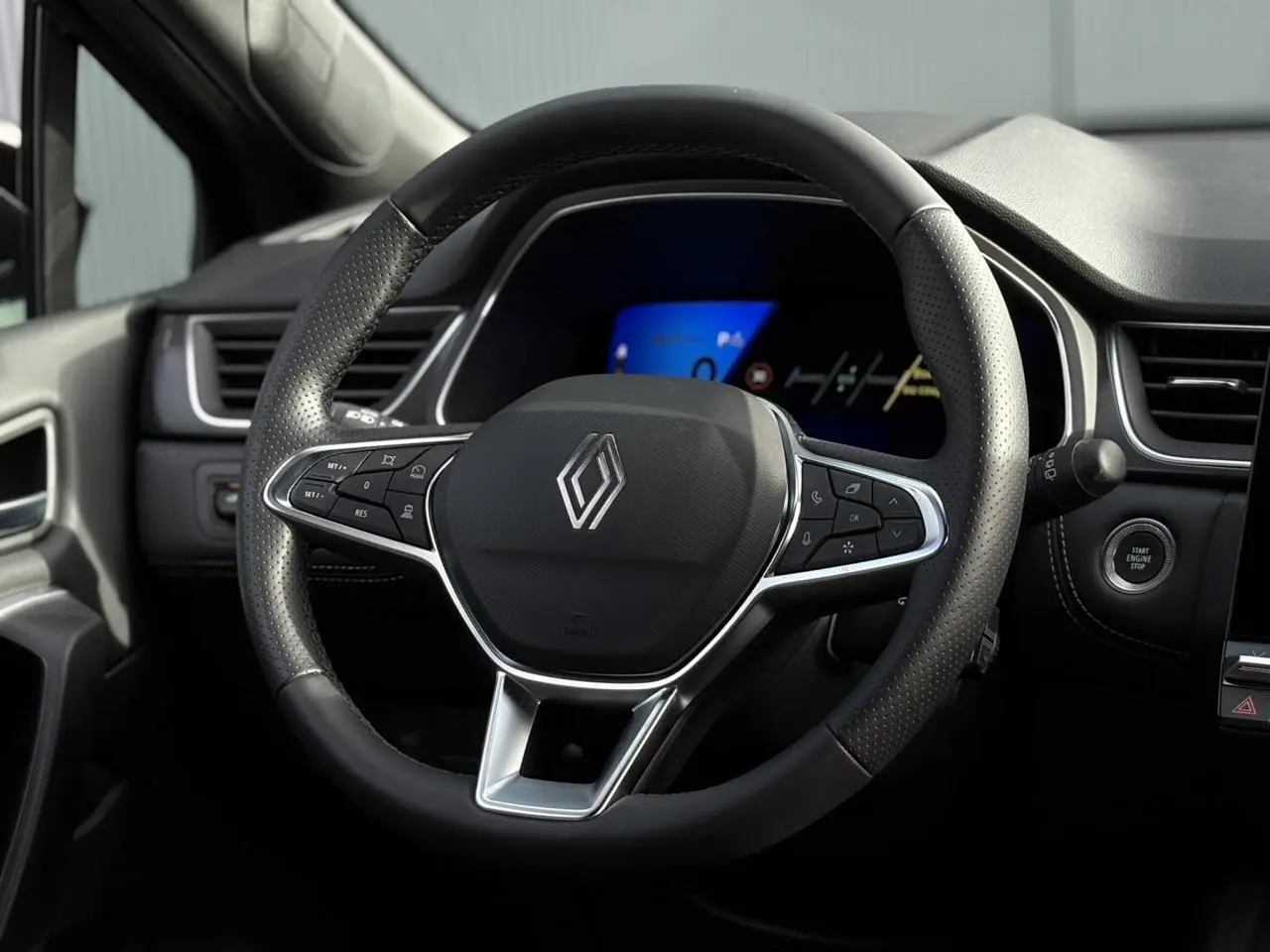 Vue rapprochée du volant noir perforé de la Renault SYMBIOZ 2025 avec commandes intégrées et tableau de bord numérique.