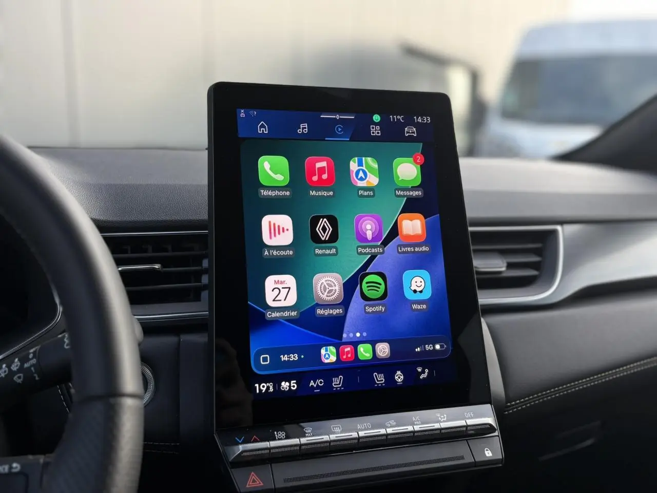 Vue intérieure centrée sur l'écran tactile vertical du système multimédia du Renault Symbioz 2025, volant partiellement visible.