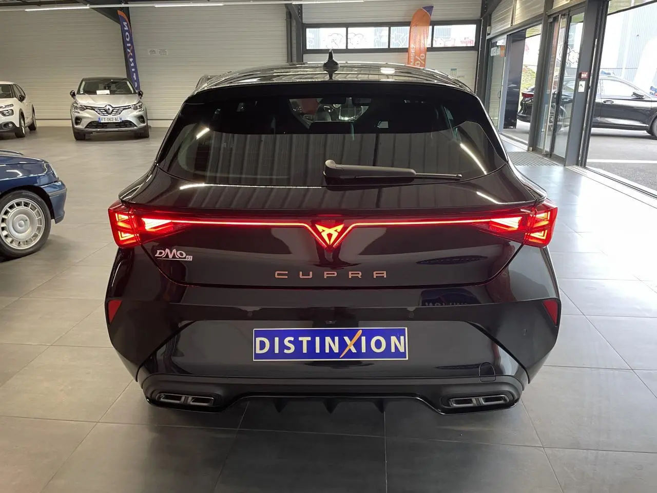 Vue arrière d'une CUPRA Leon noire avec feux arrière en bandeau lumineux et double sortie d'échappement stylisée.
