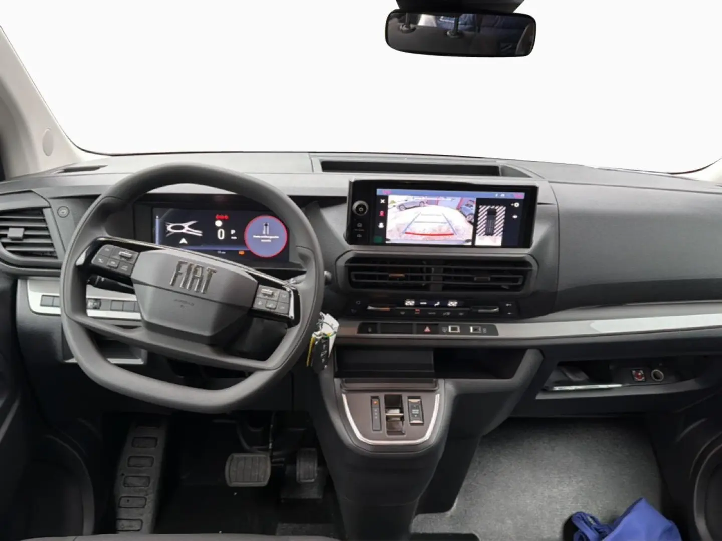 Vue intérieure avant du tableau de bord gris foncé du Fiat Scudo Combi 2026 avec écran tactile et volant multifonctions.