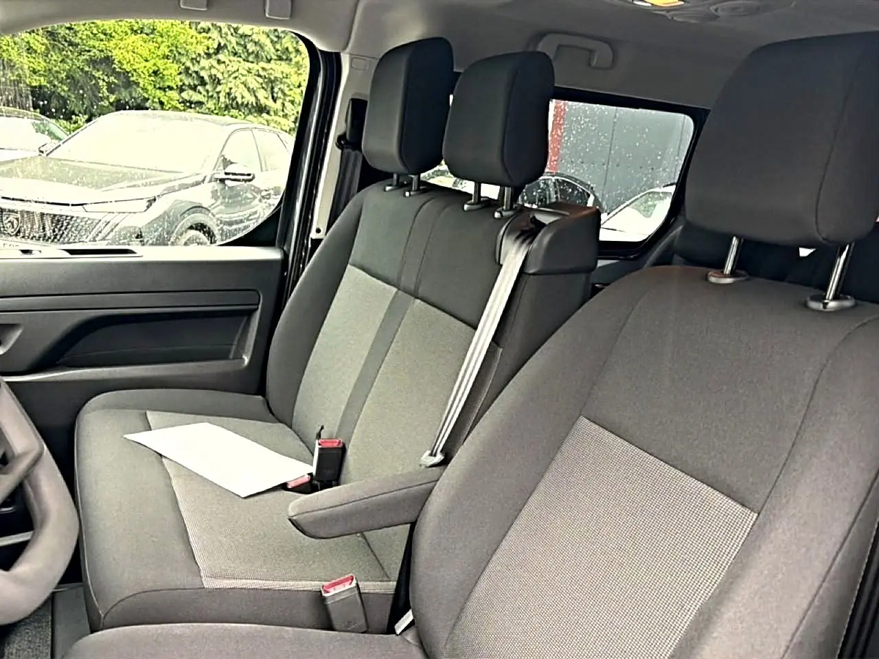 Vue intérieure côté gauche du Fiat Scudo Combi 2026, sièges bi-ton gris avec accoudoir central et ceinture de sécurité.