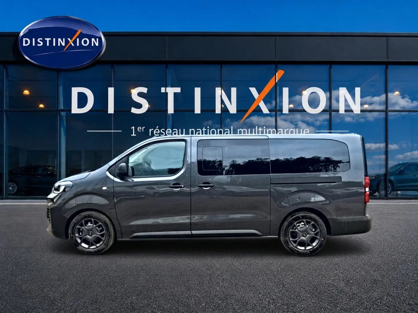 Profil droit du FIAT Scudo Combi gris titane avec porte latérale coulissante, stationné devant une vitrine Distinxion.