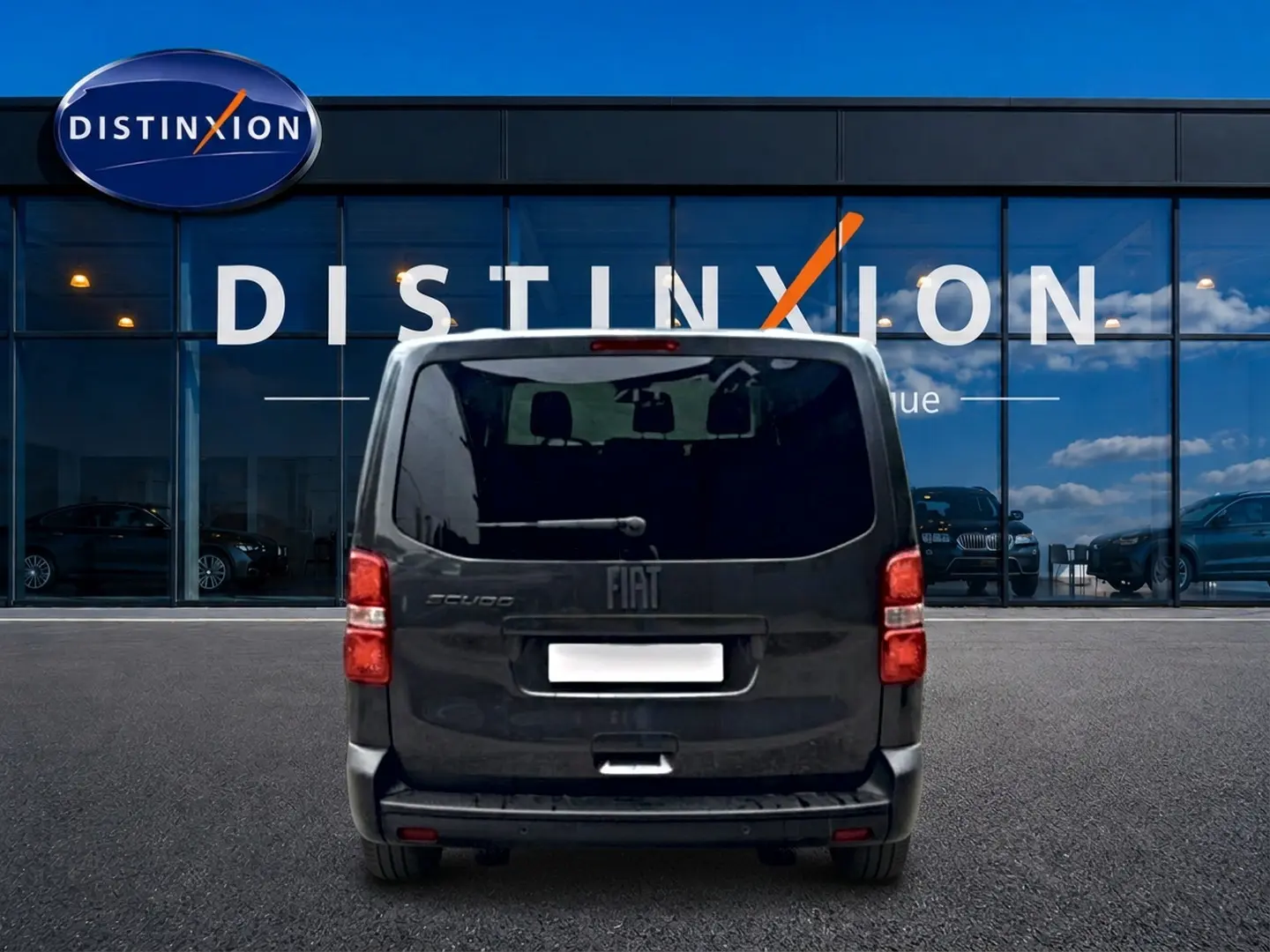 Vue arrière du FIAT Scudo Combi gris titane, porte latérale coulissante visible, stationné devant une vitrine Distinxion.