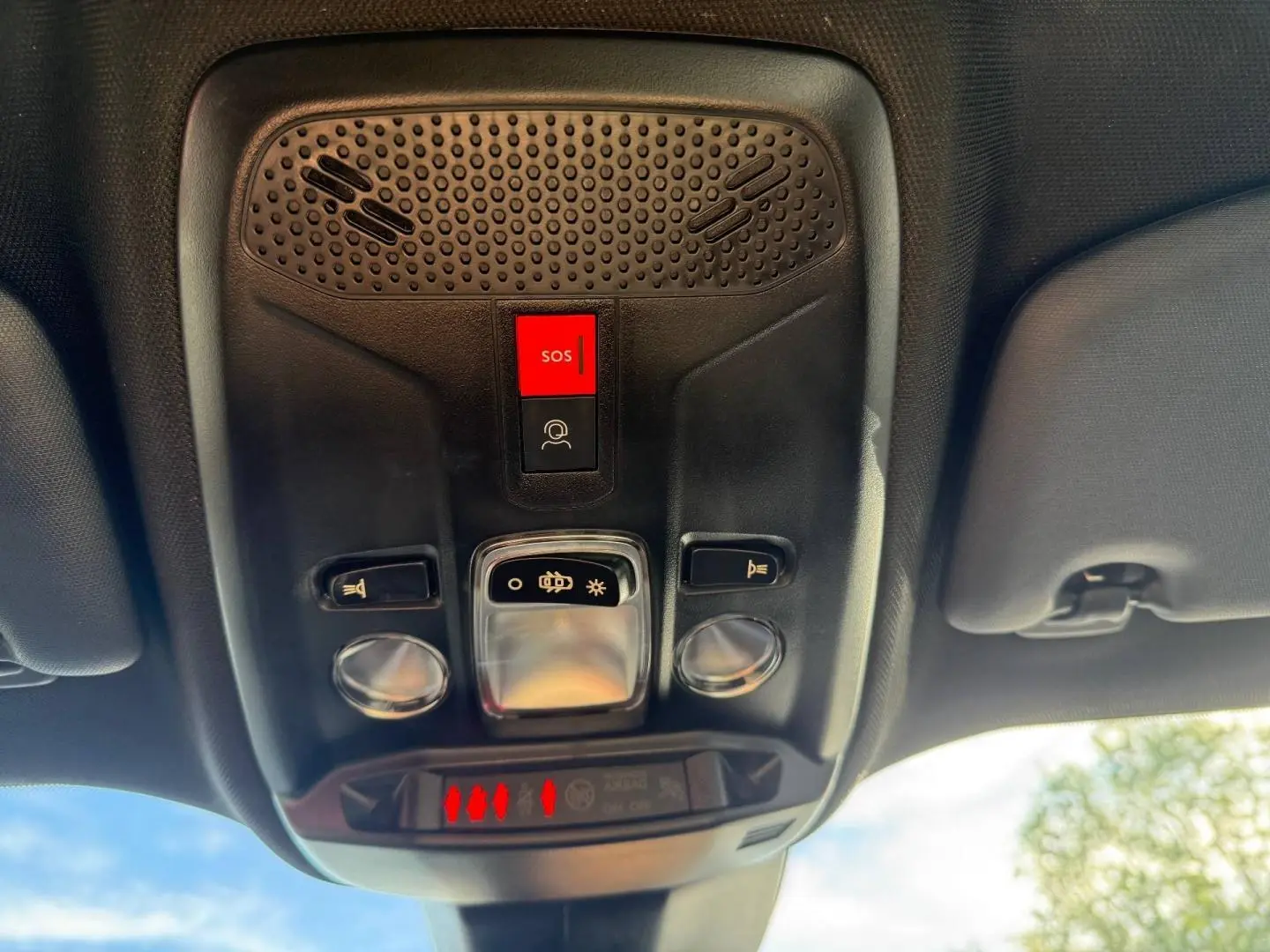 Vue en gros plan du plafonnier intérieur noir du Peugeot e-2008 avec bouton SOS rouge et commandes d’éclairage.