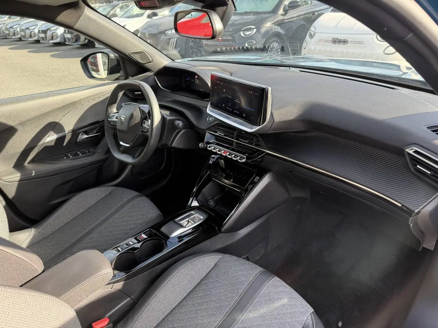 Vue intérieure côté conducteur du Peugeot e-2008 2025, avec tableau de bord noir et écran tactile central.