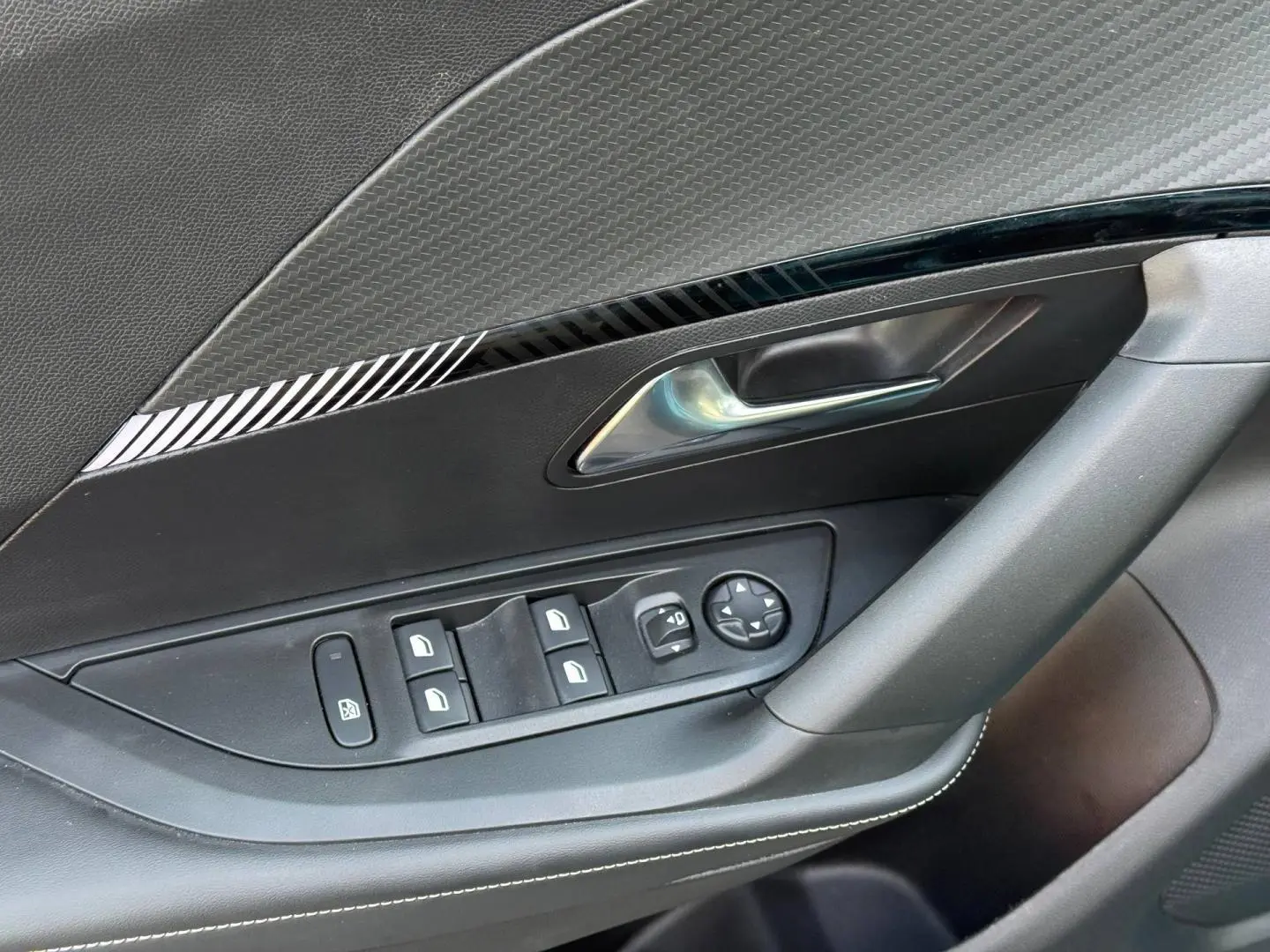 Gros plan sur la porte côté conducteur du Peugeot e-2008 2025, avec commandes électriques et garniture noire.