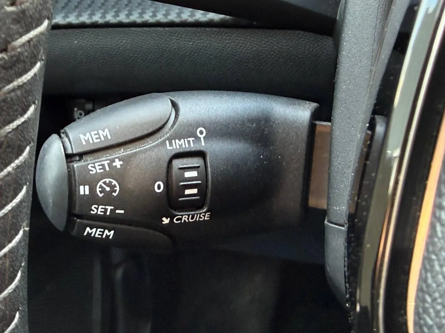 Gros plan sur la commande de régulateur de vitesse au volant d'un Peugeot e-2008 bleu Obsession.