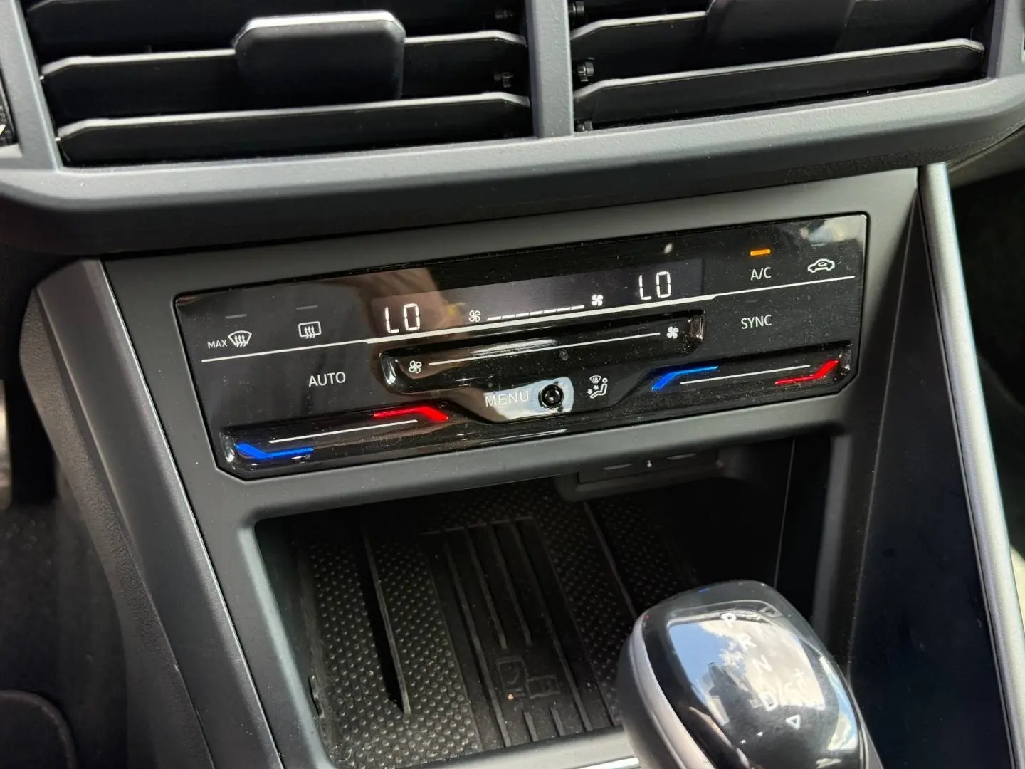 Gros plan sur la console centrale du Volkswagen Taigo 2025, montrant la climatisation bi-zone et le levier de vitesses automatique.