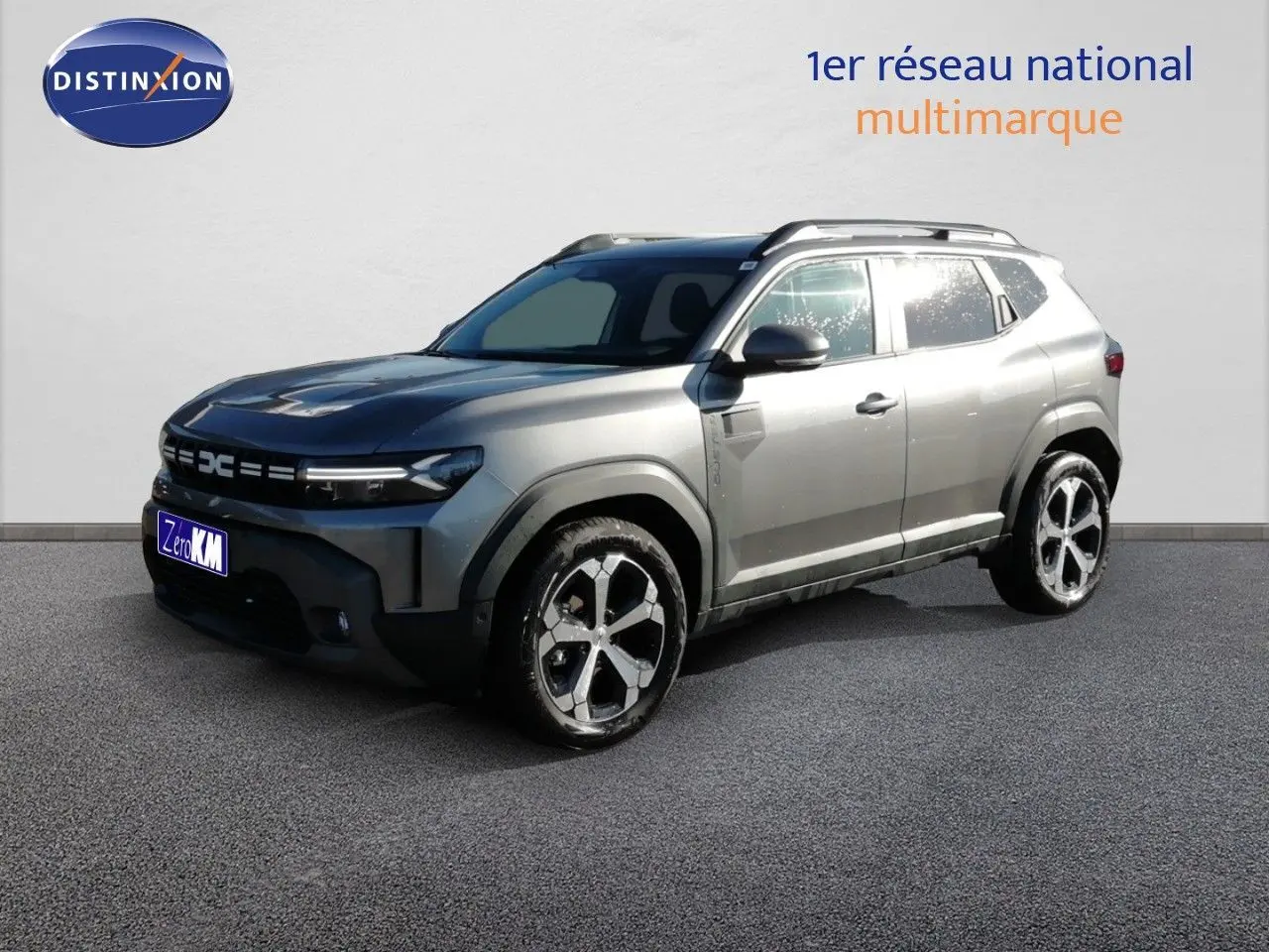 Vue 3/4 avant droit d’un Dacia Duster TCE MHEV 140ch Journey gris schiste métal avec jantes biton et barres de toit.